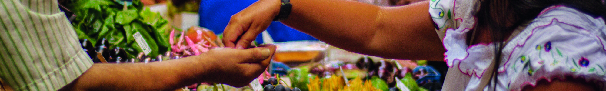 Woman paying a man for fresh vegetables at a market stall